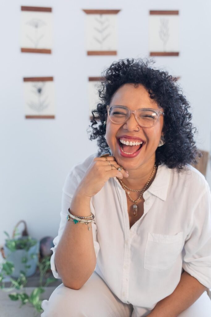 Valentina sonriendo, sentada entre plantas en la Casa de Sanación
