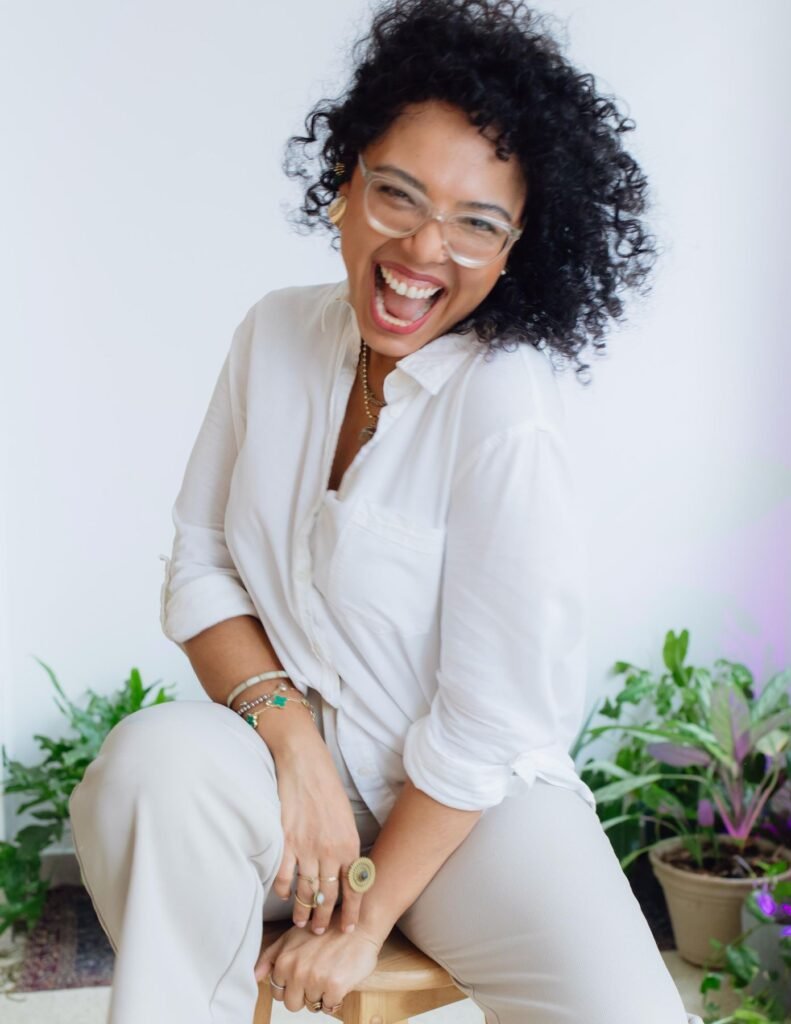 Valentina Padrón sonriendo, sentada entre plantas en Casa de Sanación